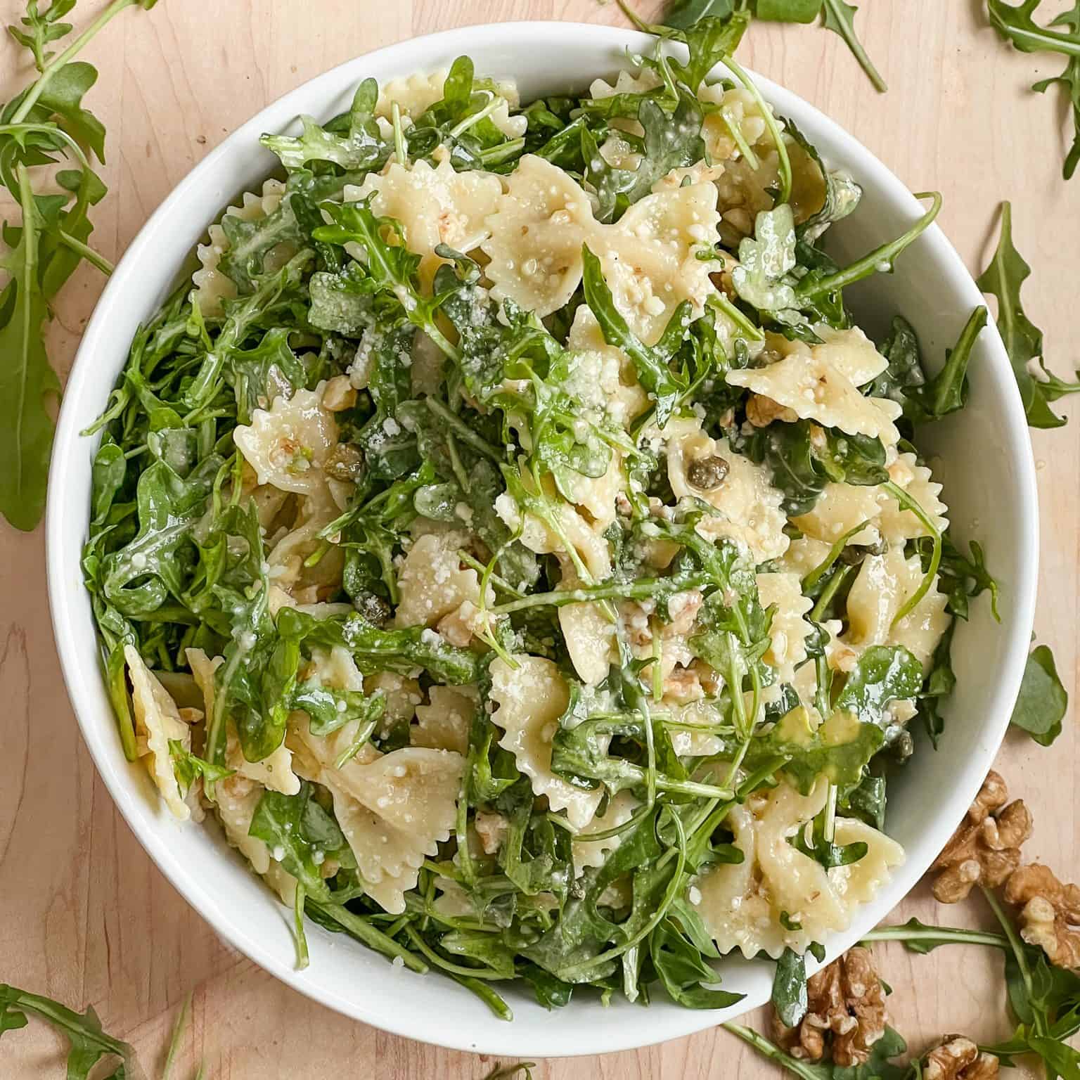 Lemon arugula pasta salad in white round bowl. Image from above, featured image